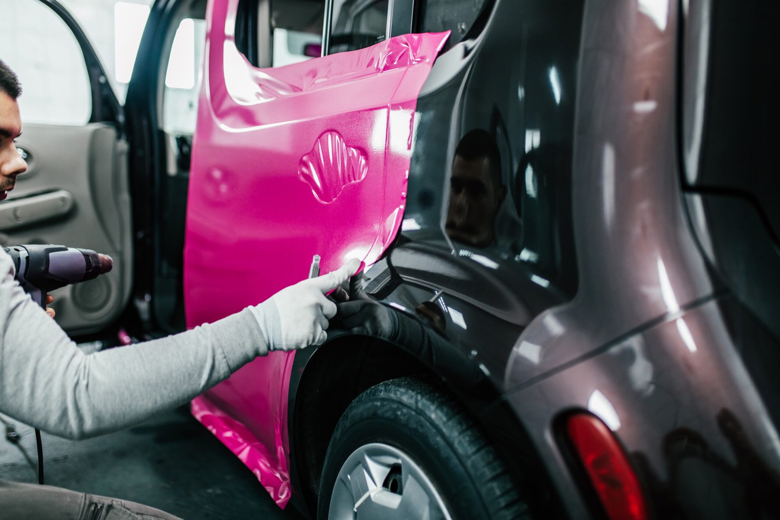 Car wrapping specialist putting vinyl foil or film on car. Selective focus.